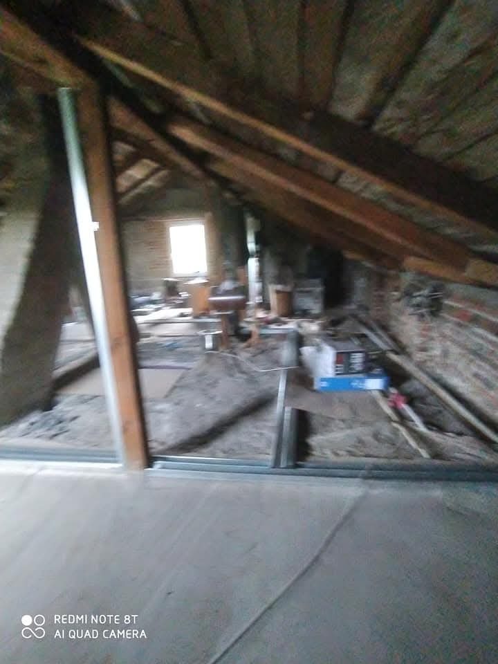 Adaptacja poddasza: widok na drewnianą konstrukcję dachu, fragment nowej wylewki podłogowej oraz profile pod zabudowę ścian działowych w trakcie prac remontowych.