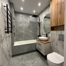 New House - Nowoczesna łazienka w Gliwicach z szarymi płytkami imitującymi marmur, czarną armaturą, owalnym lustrem i drewnianą szafką wiszącą.