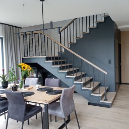 Phu eurokrys Krystian Kozioł - Nowoczesne schody z metalową balustradą i drewnianymi stopniami w minimalistycznym wnętrzu z jadalnią, oświetlone wiszącą lampą.