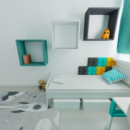 Wojciech Polański - Pokój dziecięcy z białym łóżkiem, biurkiem i regałami kostkami w kolorach turkusowym, białym i szarym. Na ścianie dekoracja przypominająca klocki lego. Na podłodze dywan z motywem kosmicznym.