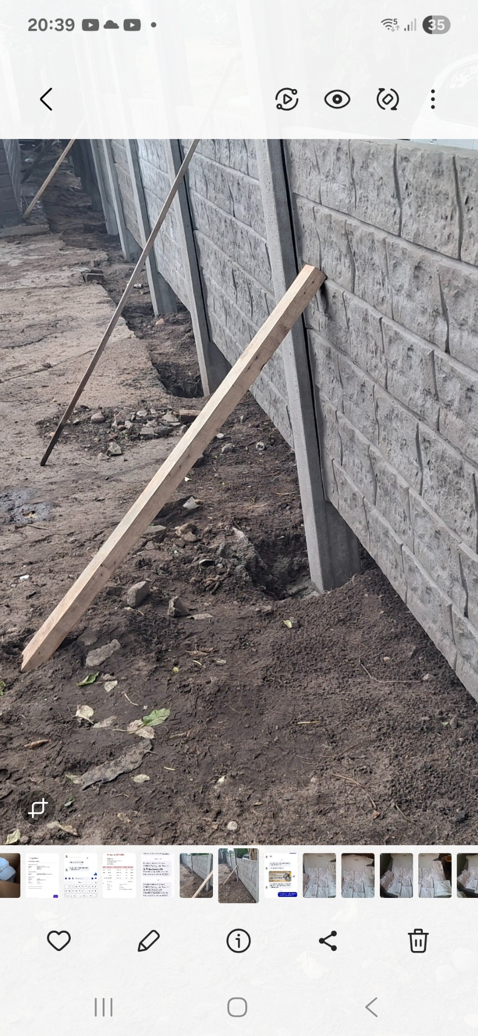 Fragment montowanego ogrodzenia betonowego z drewnianą podporą, ukazujący etap wkopania słupków w ziemię. Widoczne elementy konstrukcyjne i surowy teren.