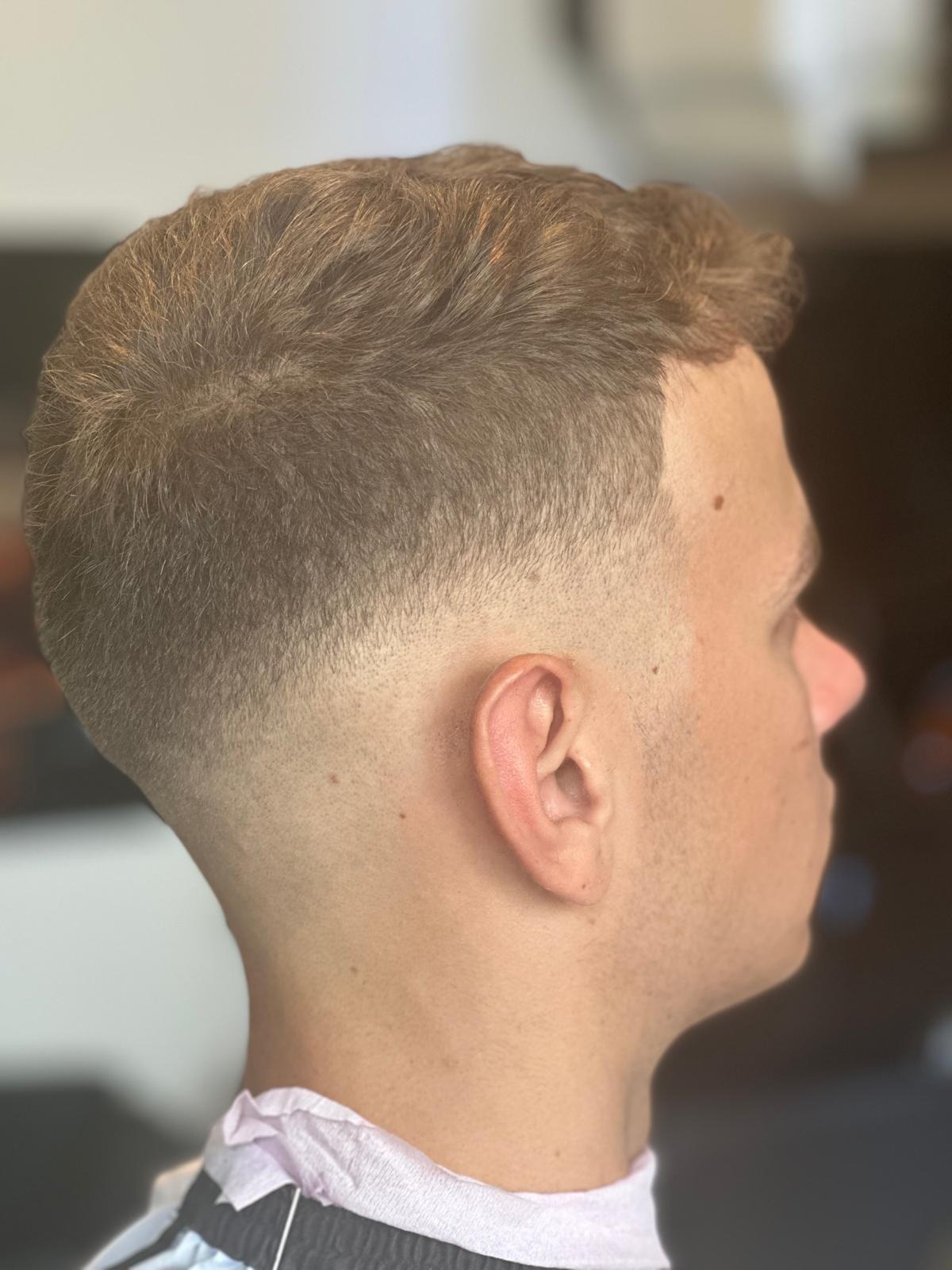 Męska fryzura z cieniowaniem, widok z profilu, z bliska, widoczne szczegóły strzyżenia i przejścia kolorów.