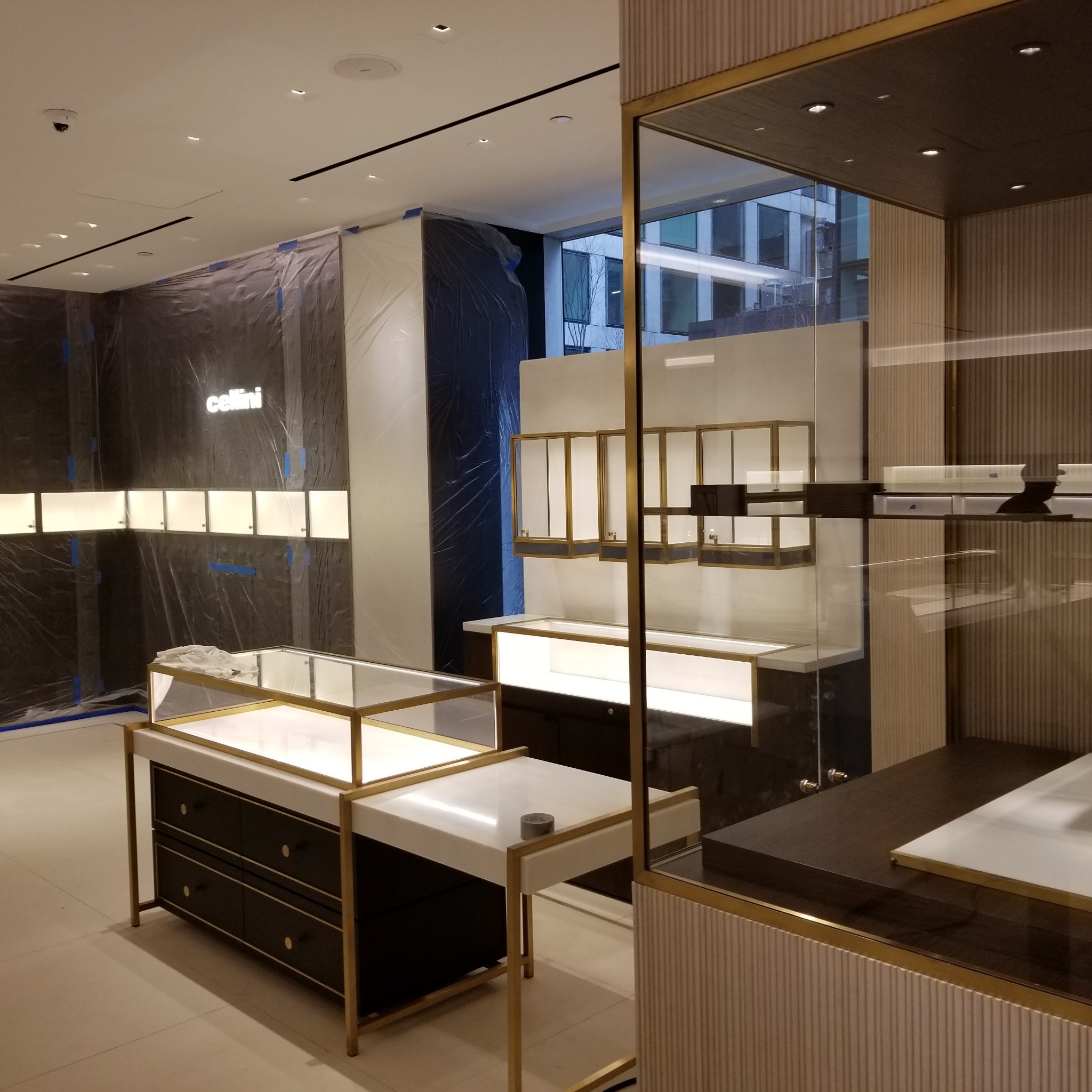 Wnętrze sklepu jubilerskiego w trakcie aranżacji: witryny z oświetleniem, osłonięte folią ściany, nowoczesny design.
