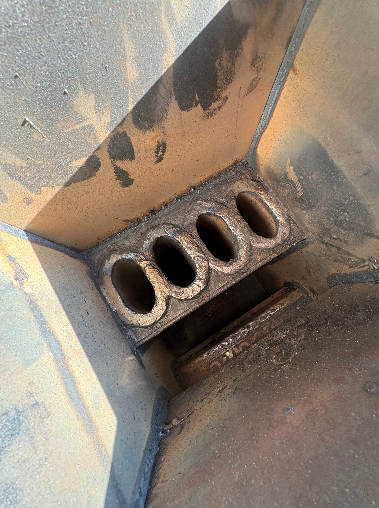 Wewnętrzny widok spawanej konstrukcji z czterema owalnymi otworami, widoczne spoiny i ślady obróbki.