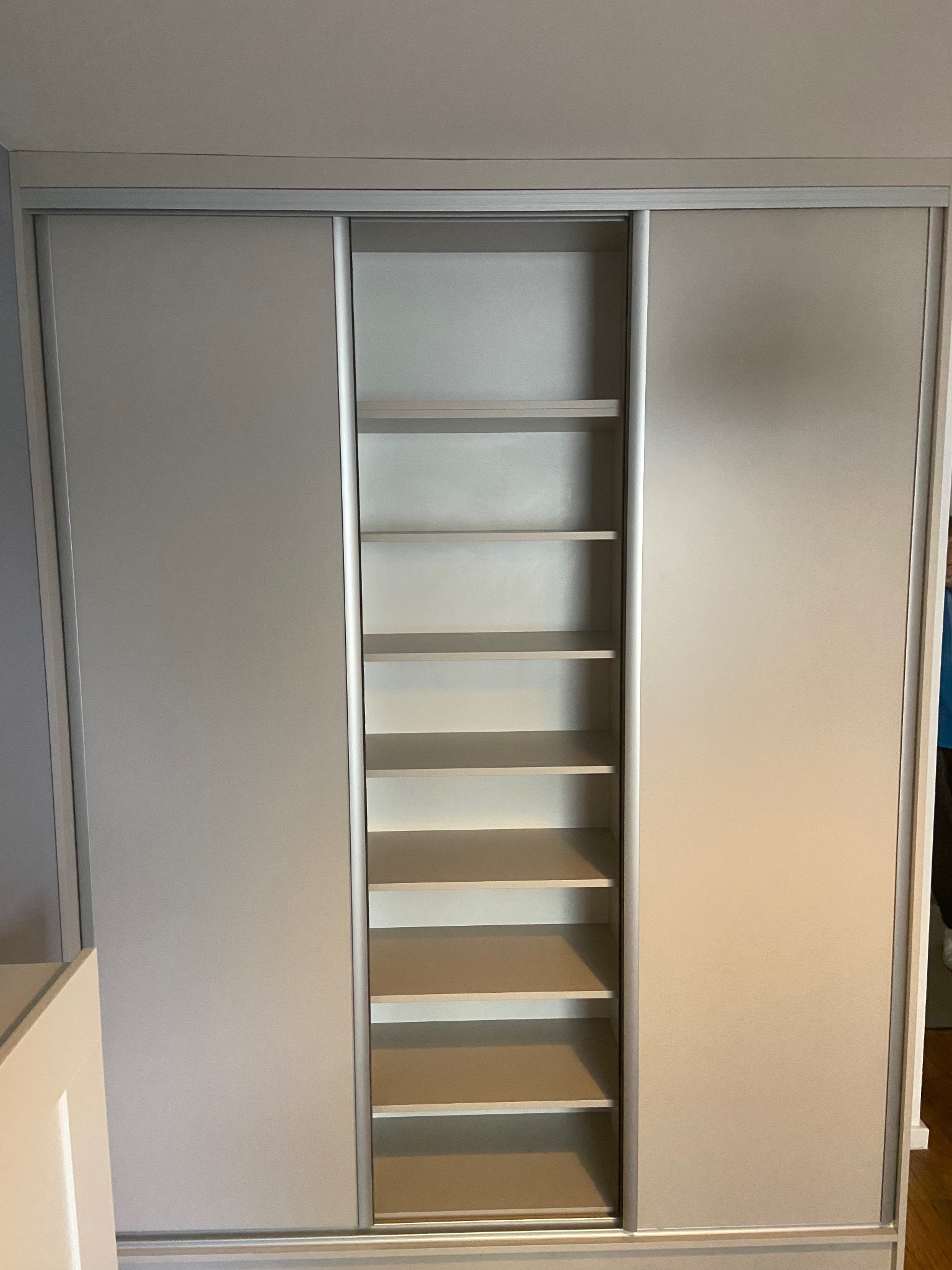 Jasna szafa wnękowa z przesuwnymi drzwiami i otwartą częścią z półkami, widok z bliska, minimalistyczny design.