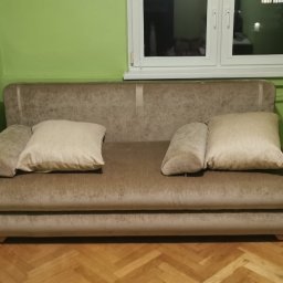 Martyna Klimczak Firma Sprzątająca - Beżowa sofa z poduszkami w pokoju z zielonymi ścianami i drewnianą podłogą, widoczne naklejki piłkarskie na ścianie.