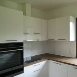 Nowoczesna, biała zabudowa kuchenna z drewnianym blatem, płytą indukcyjną i piekarnikiem Electrolux, wykończona białymi, prostokątnymi płytkami.