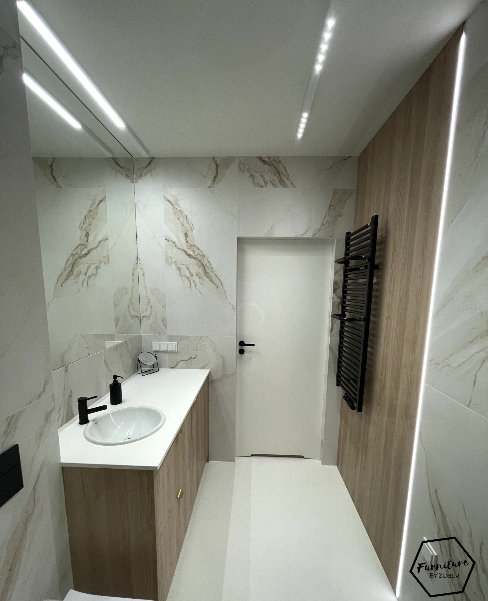 Nowoczesna łazienka w Trzebnicy z umywalką nablatową na drewnianej szafce, marmurowe płytki na ścianach, czarny grzejnik drabinkowy i oświetlenie LED.