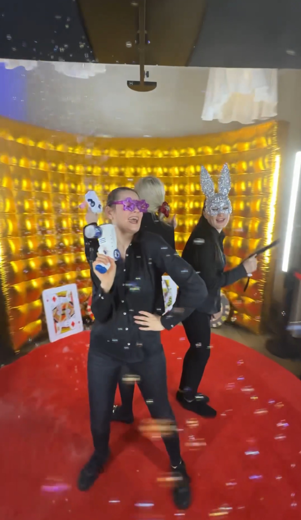 Uczestnicy sesji zdjęciowej w Poznaniu, w przebraniach i okularach w kształcie gwiazd, bawią się wewnątrz złotej dekoracji, otoczeni bańkami mydlanymi.