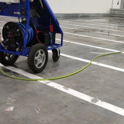 ELEPHANT CLEAN M&K - Wózek z urządzeniem wysokociśnieniowym do czyszczenia przemysłowego na hali produkcyjnej, widoczny napis 'STREFA BIO' na ścianie w tle.