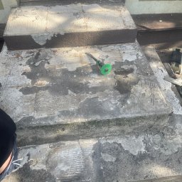 Pro bud compani - Schody wejściowe z usuniętymi płytkami, widoczne ślady po kleju i narzędzie do cięcia płytek z zieloną tarczą.