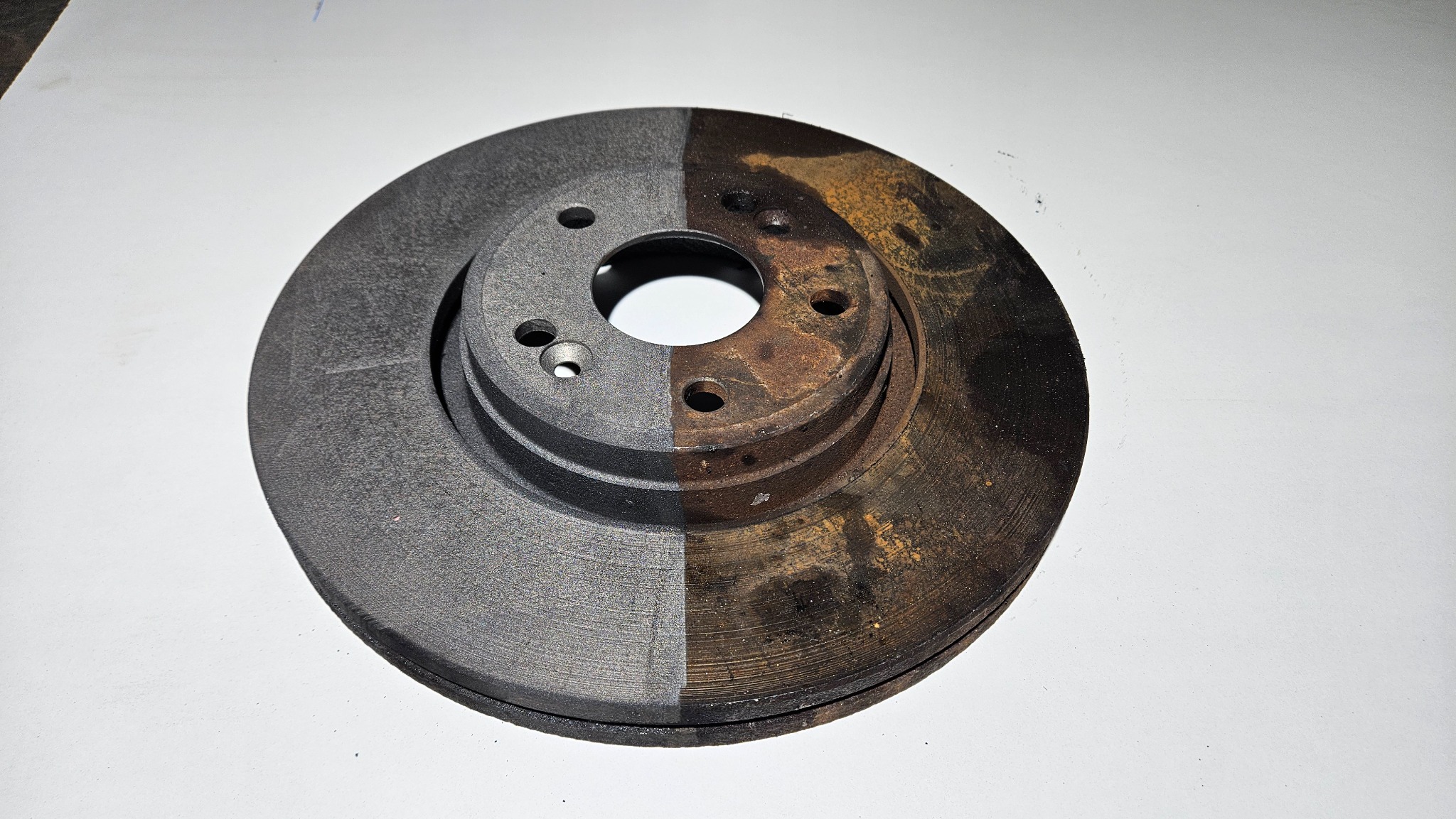 Tarcza hamulcowa w połowie oczyszczona z rdzy, prezentująca kontrast między powierzchnią po obróbce a skorodowaną.