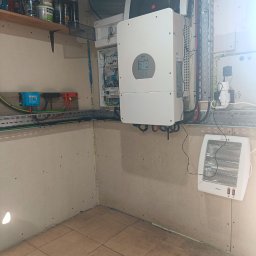 ART MUSIC OBSŁUGA MUZYCZNA IMPREZ LISZEWSKI ARKADIUSZ - Wnętrze z zamontowanym inwerterem solarnym Daye, rozdzielnicą elektryczną i grzejnikiem elektrycznym. Widoczne kable i przewody w korytkach.