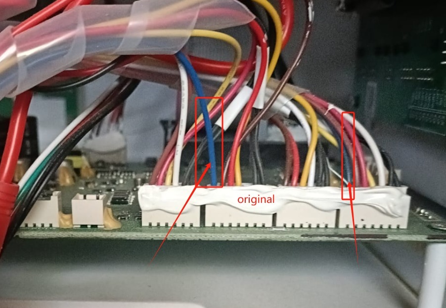 Szczegółowe zbliżenie na podłączenie kabli w złączu elektrycznym, zabezpieczone białą masą uszczelniającą. Widoczne kolorowe przewody i elementy elektroniki.