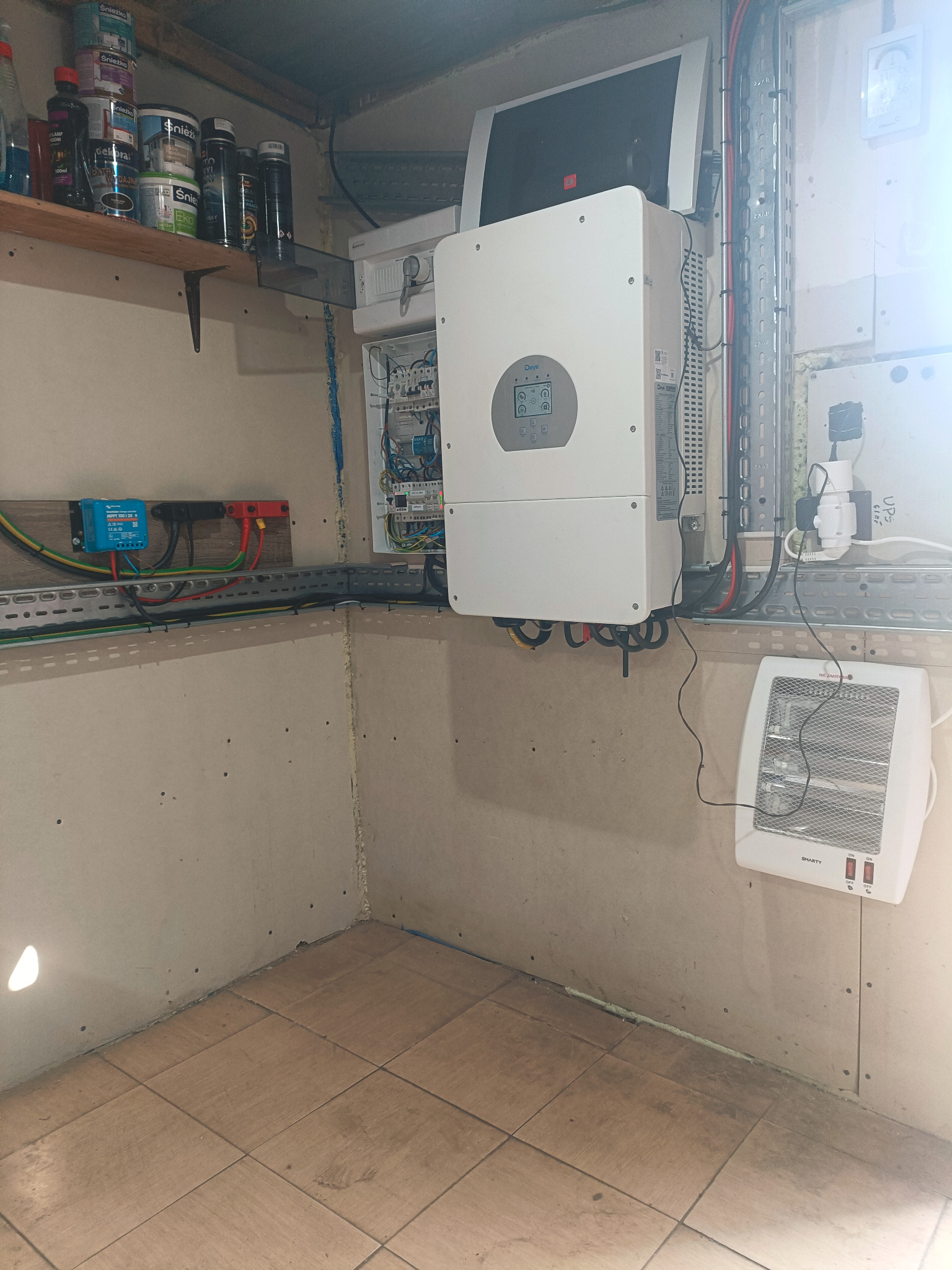 Wnętrze z zamontowanym inwerterem solarnym Daye, rozdzielnicą elektryczną i grzejnikiem elektrycznym. Widoczne kable i przewody w korytkach.