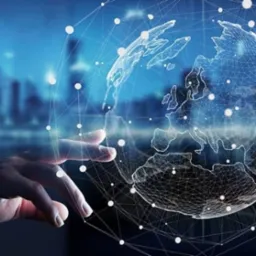 Ręka dotyka wirtualnej siatki globu na tle rozmytego miejskiego krajobrazu, symbolizując globalne połączenia i technologie.