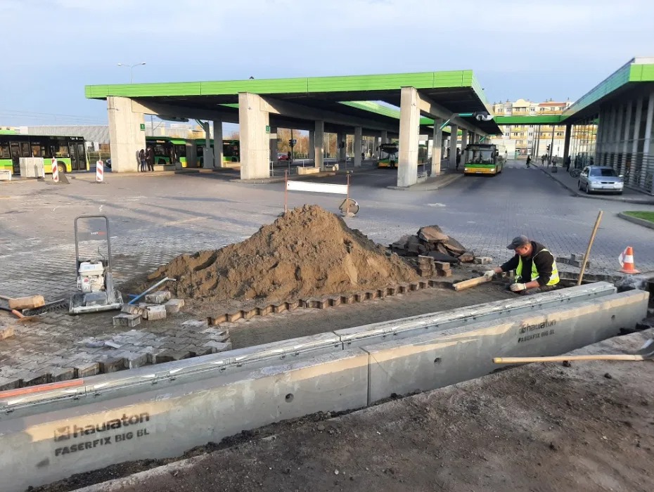 Pracownik wyrównuje podsypkę pod kostkę brukową na terenie dworca autobusowego, widoczna ubijarka i elementy odwodnienia liniowego Hauaton Faserfix Big BL.