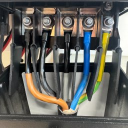 Dobra wydajność ROMAN DERKACH - Szczegółowe ujęcie złącza elektrycznego z kolorowymi przewodami (pomarańczowy, czarny, niebieski, żółto-zielony) w instalacji fotowoltaicznej.