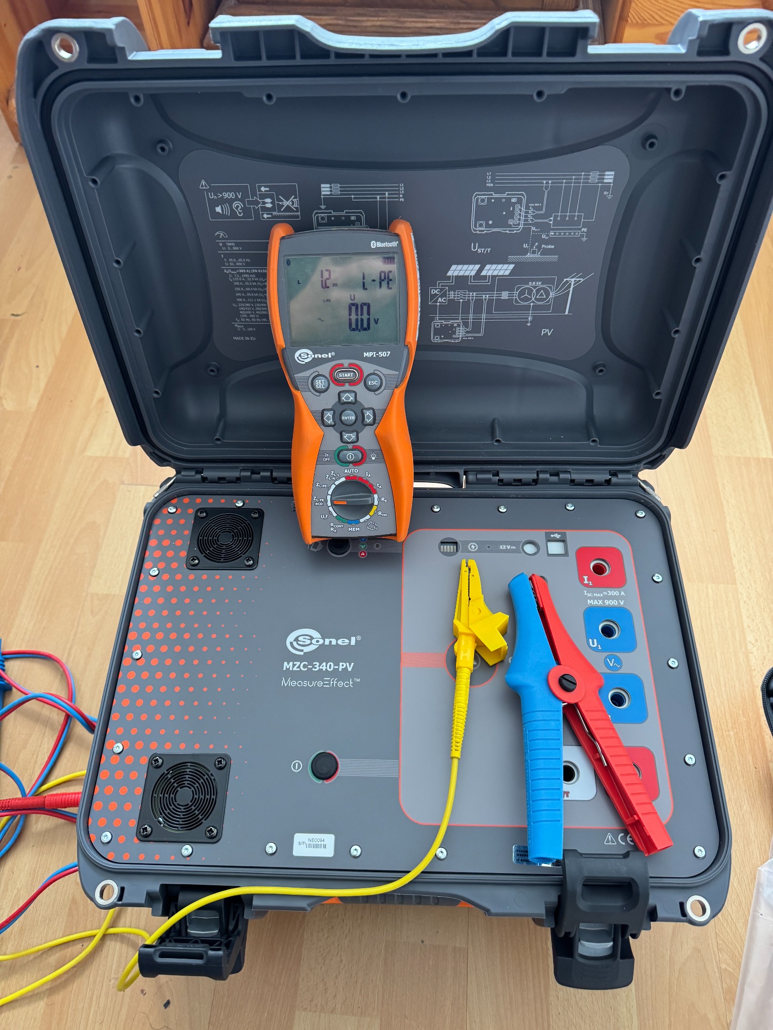 Otwarta walizka z urządzeniem Sonel MZC-340-PV i miernikiem MPI-507, używane do pomiarów i diagnostyki instalacji fotowoltaicznych, z żółtymi i czerwono-niebieskimi klemami.