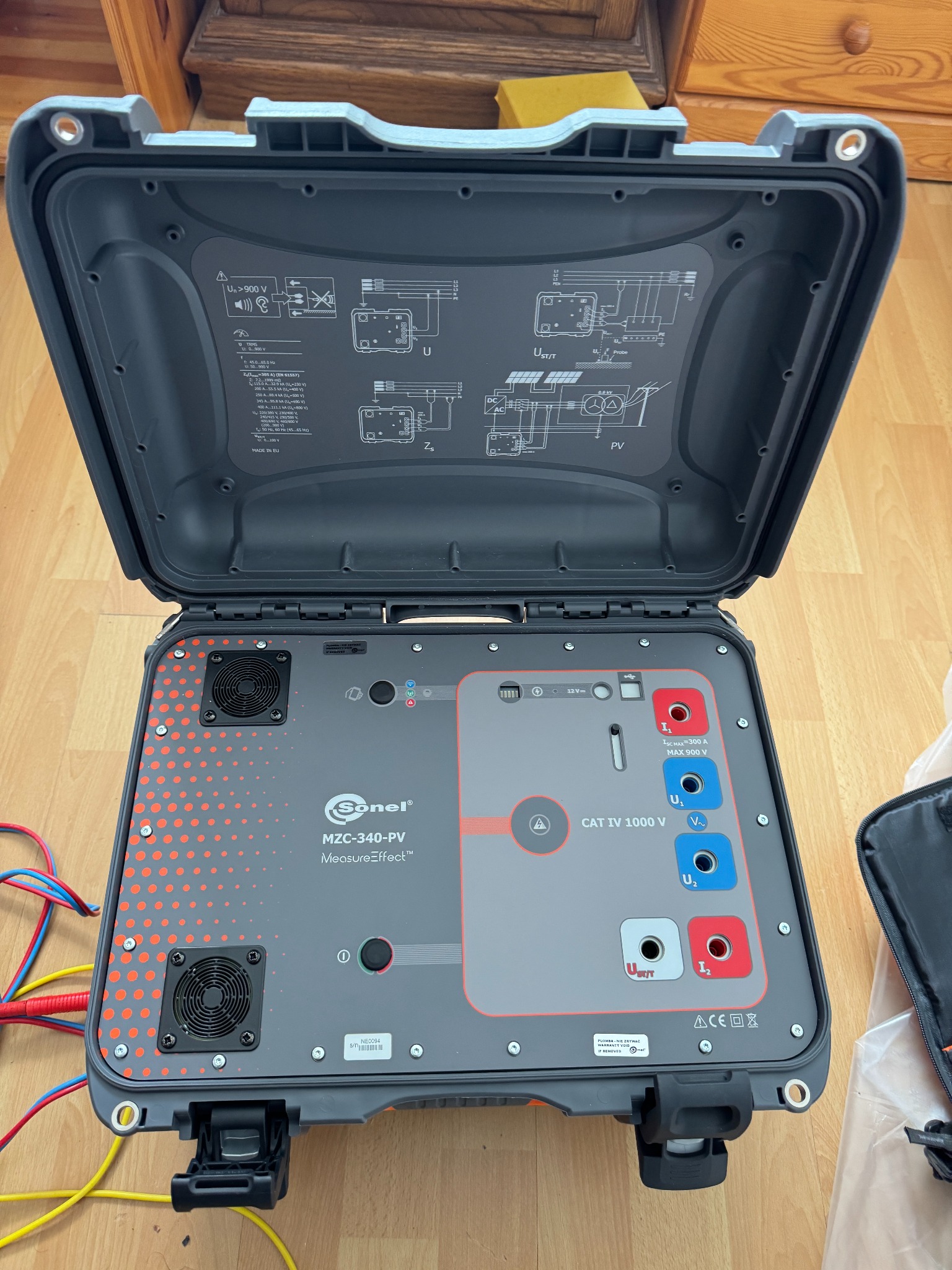 Otwarty tester instalacji fotowoltaicznych Sonel MZC-340-PV w szarej obudowie z czerwonymi akcentami, widoczne gniazda pomiarowe, wentylatory i schemat instalacji na pokrywie.