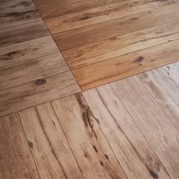 Marian Jankowski - Ułożone panele podłogowe w odcieniach brązu i szarości, z widoczną strukturą drewna i naturalnymi usłojeniami, tworzące geometryczny wzór.