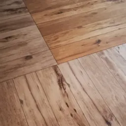 Ułożone panele podłogowe w odcieniach brązu i szarości, z widoczną strukturą drewna i naturalnymi usłojeniami, tworzące geometryczny wzór.