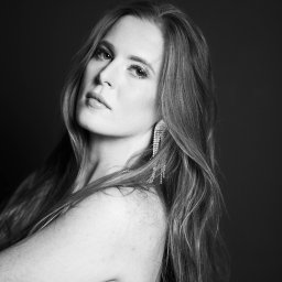 STUDIO KREATYWNE Katarzyna Ćwiertnia - Portret kobiety z długimi włosami i wiszącymi kolczykami na czarnym tle w Poznaniu, wykonany w czerni i bieli.