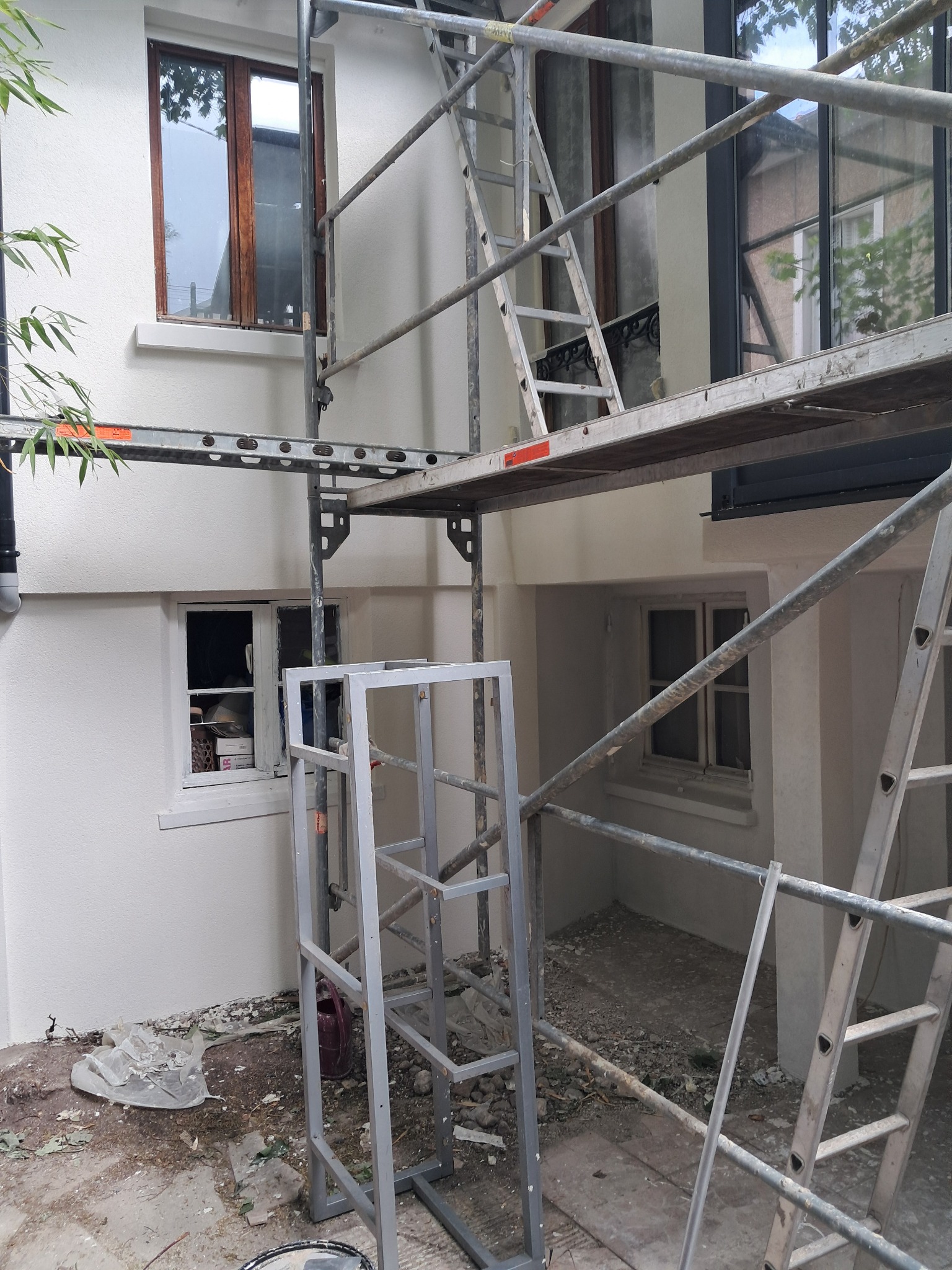 Elewacja po malowaniu w Jarosławiu, widoczna z rusztowania. Świeży biały kolor, okna z drewnianą ramą i fragment zieleni w tle. Prace elewacyjne w toku.