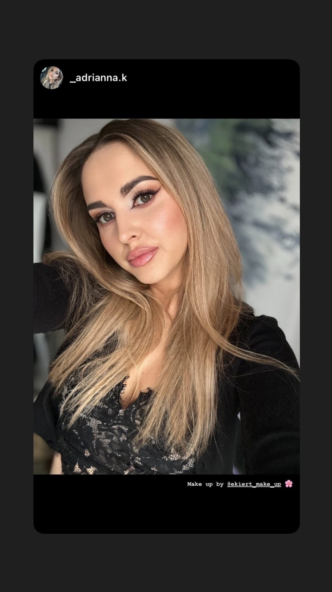 Portret kobiety z profesjonalnym makijażem oczu i ust, blond włosy opadające na ramiona, czarna bluzka z koronką, delikatne oświetlenie.