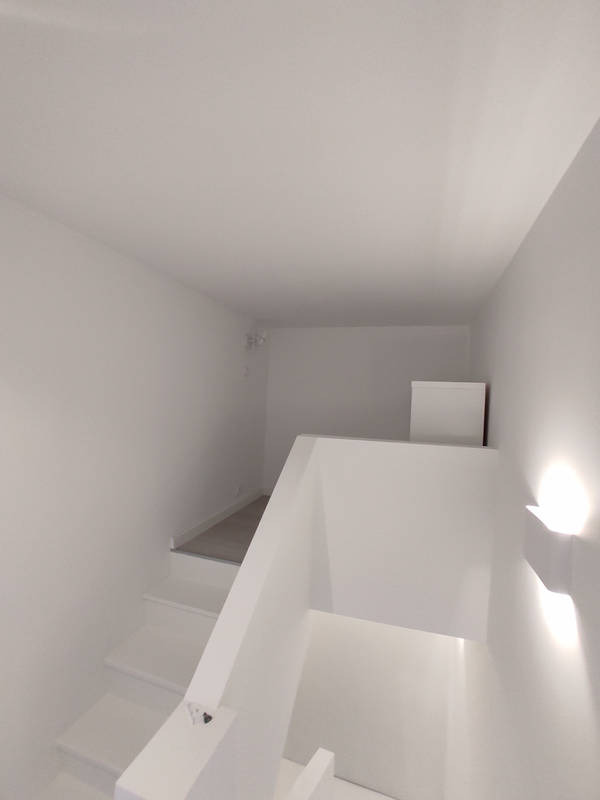 Białe schody z oświetleniem ściennym w minimalistycznym wnętrzu, widok z góry na dół.