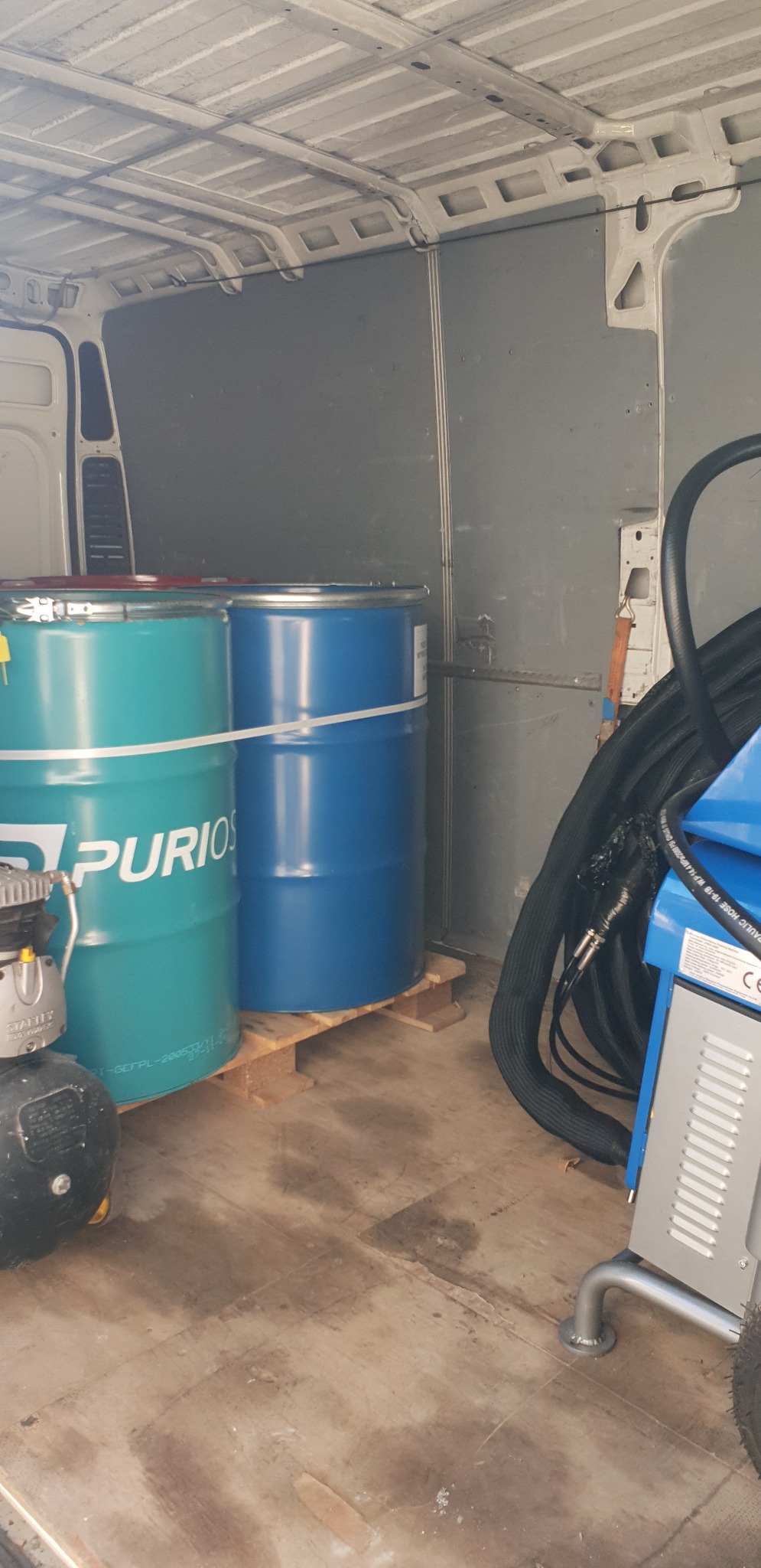 Wnętrze furgonetki w Białymstoku z dwoma beczkami z pianką i sprzętem do natrysku piany na palecie, gotowe do użycia.