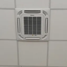 Klimatyzator kasetonowy marki Gree zamontowany w suficie podwieszanym, widoczny wyświetlacz temperatury.