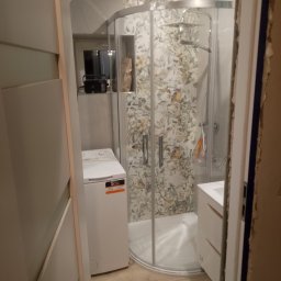 WLAD-BUD - Kompaktowa łazienka po remoncie: kabina prysznicowa z wzorzystymi płytkami, pralka i umywalka z szafką. Widok zza framugi drzwi.