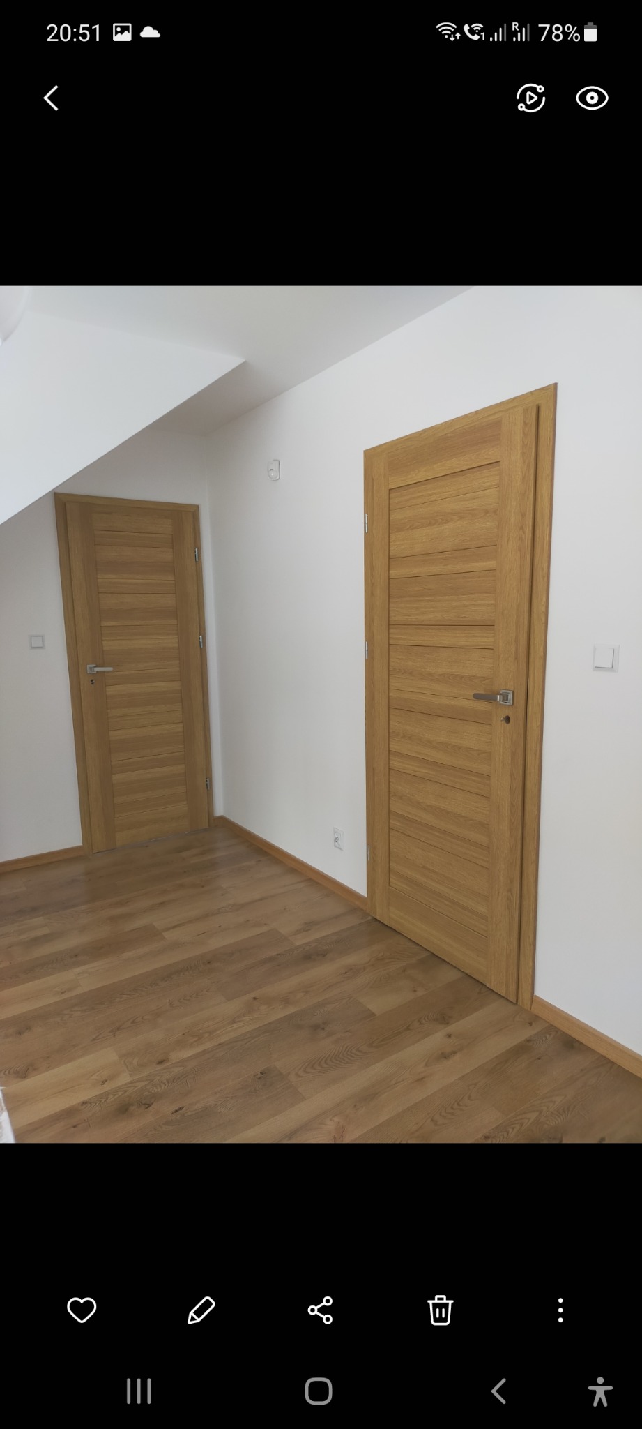 Dwa drewniane drzwi wewnętrzne z poziomymi panelami i srebrnymi klamkami, zamontowane w nowym, białym pokoju z podłogą z paneli w odcieniach brązu.