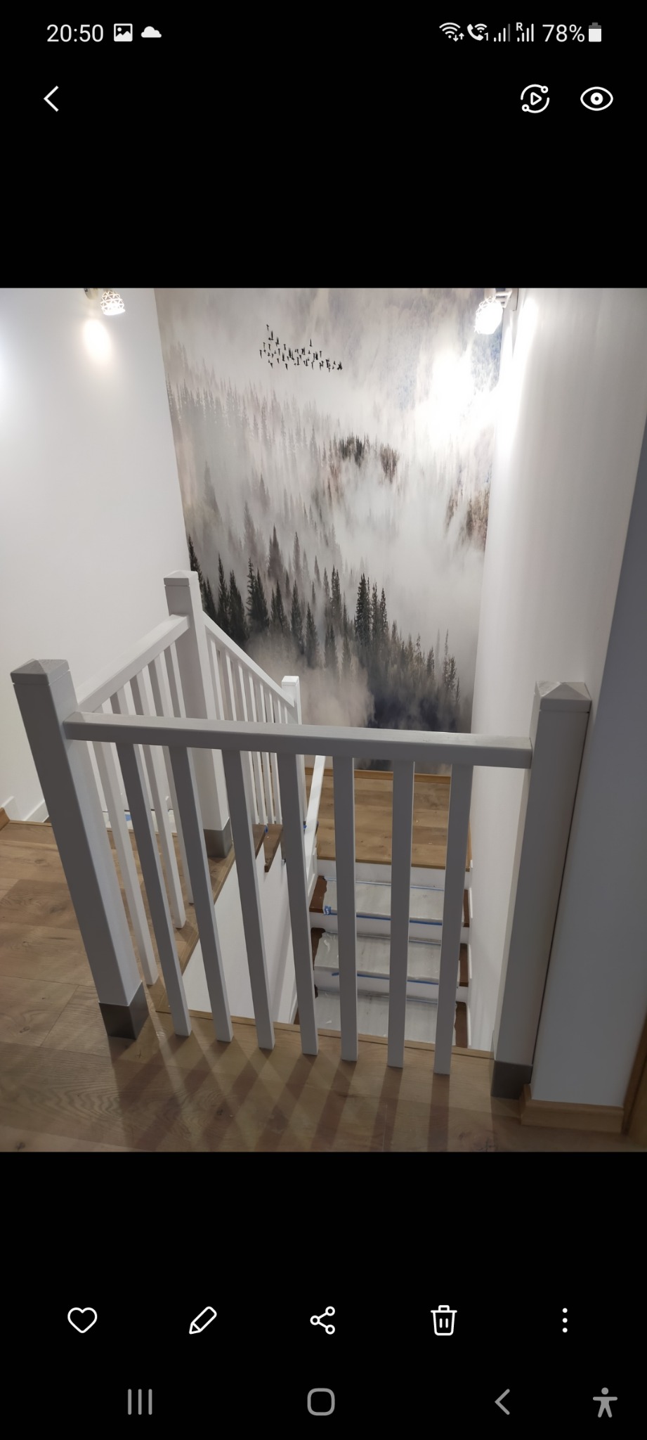 Biała balustrada schodów z widokiem na fototapetę z motywem mglistego lasu i sylwetkami ptaków, drewniana podłoga.