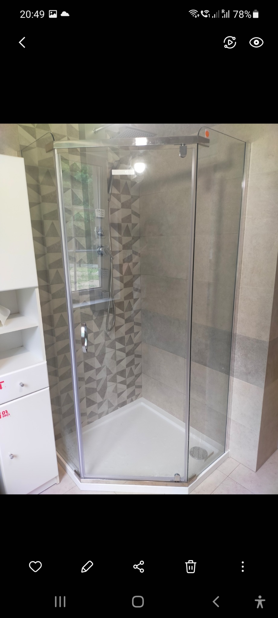 Szklana kabina prysznicowa narożna z brodzikiem, zamontowana w łazience z geometrycznymi płytkami na ścianie i oknem w tle.