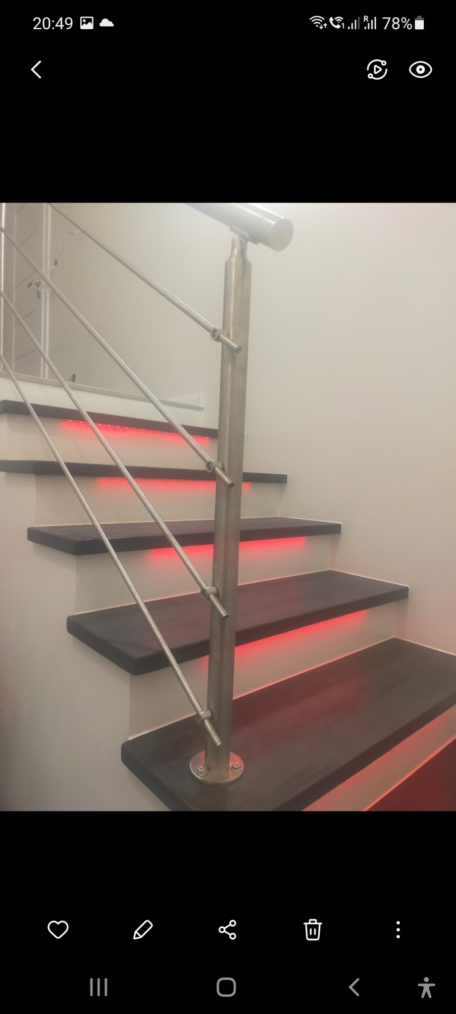 Nowoczesne schody z drewnianymi stopniami podświetlonymi czerwonym LED, z metalową balustradą.