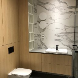 Furnilem Paweł Andrejczyn - Nowoczesna łazienka z zabudową z jasnego drewna, marmurowymi płytkami na ścianie i wiszącą toaletą.