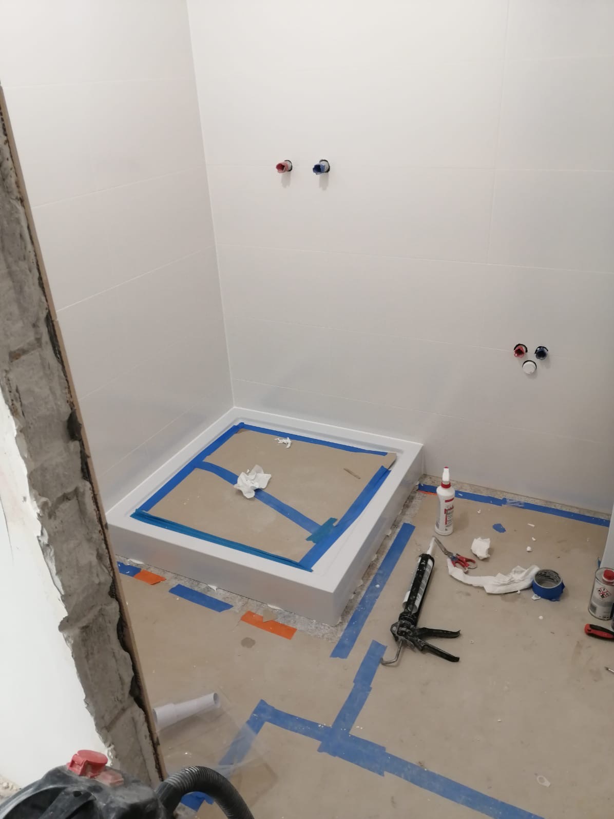 Montaż brodzika w kabinie prysznicowej w Skórzewie, zabezpieczonej taśmą malarską, widoczne narzędzia i materiały montażowe.