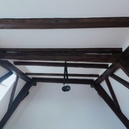 Zbigniew Dziura - Poddasze z drewnianą konstrukcją dachu, świeżo po malowaniu na biało, z widocznym głośnikiem przenośnym wiszącym na belce.