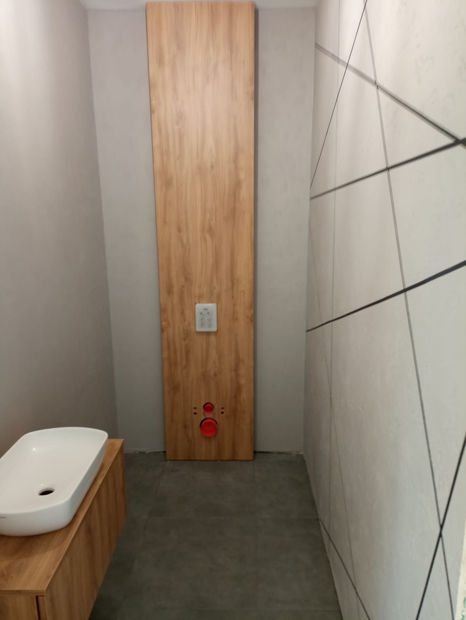 Nowoczesna łazienka z umywalką nablatową na szafce z drewnianym frontem, widoczna zabudowa stelaża WC z drewnianą okładziną i panelem sterującym.