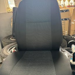 Czysta tapicera - Wyczyszczone, szare siedzenie samochodowe z wzorem w kropki, na tle opon i pudeł. Widoczne ślady wilgoci po czyszczeniu.