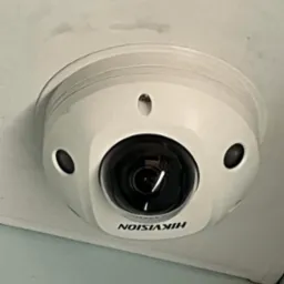 Kamera kopułkowa Hikvision zamontowana na suficie z widocznymi zabrudzeniami.