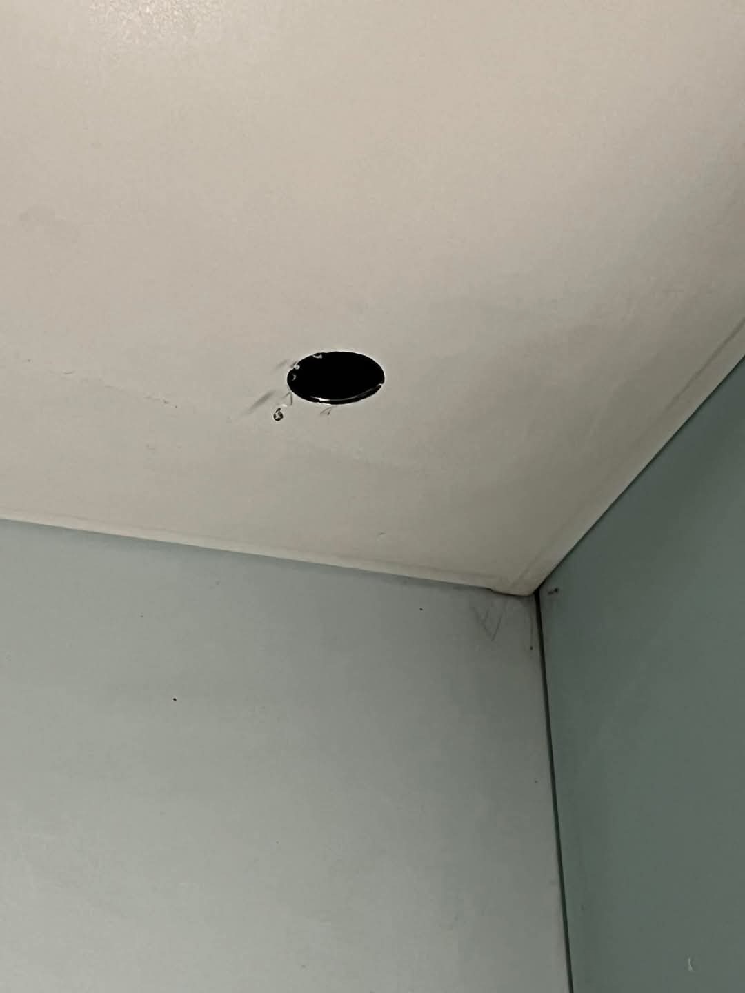 Otwór w suficie przygotowany pod montaż oświetlenia, widoczne przewody. Ściany pomalowane na jasny, błękitny kolor.