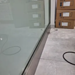 Wnętrze z widoczną szybą po umyciu, na podłodze kartony i przew&oacute;d. Widoczne odbicia w czystej szybie.