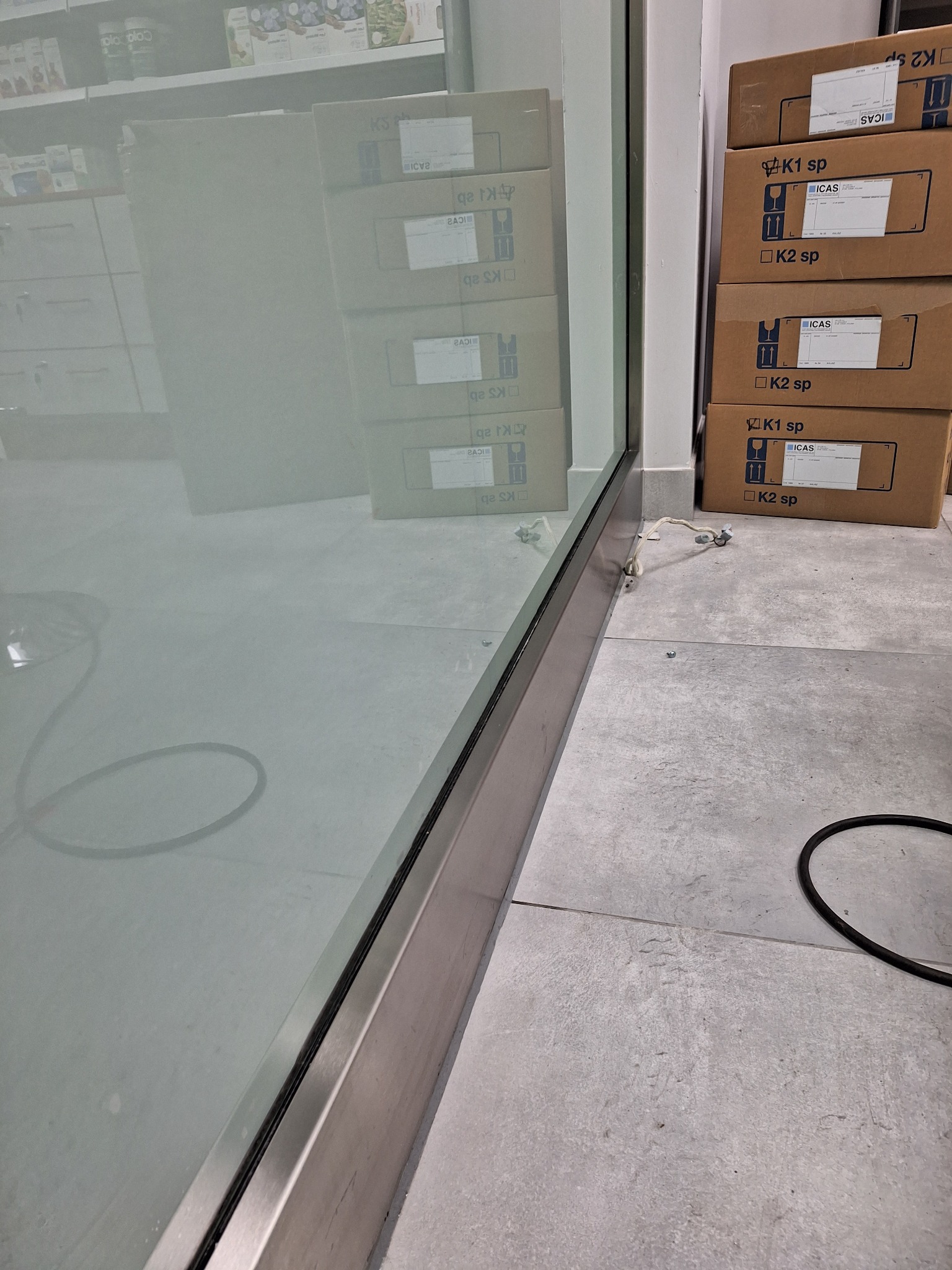 Wnętrze z widoczną szybą po umyciu, na podłodze kartony i przewód. Widoczne odbicia w czystej szybie.