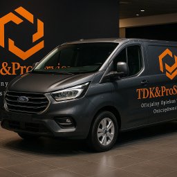 TDK&ProService - Szary Ford Transit Custom z pomarańczowym logo TDK&ProService na tle ciemnej ściany z tym samym logo. Prezentacja marki i floty pojazdów.