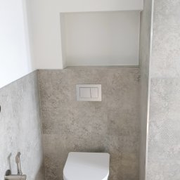 Przemysław Rolnik - Nowoczesna toaleta podwieszana z szarymi płytkami w marokański wzór, drewnopodobna podłoga i bateria bidetowa ze stali nierdzewnej.