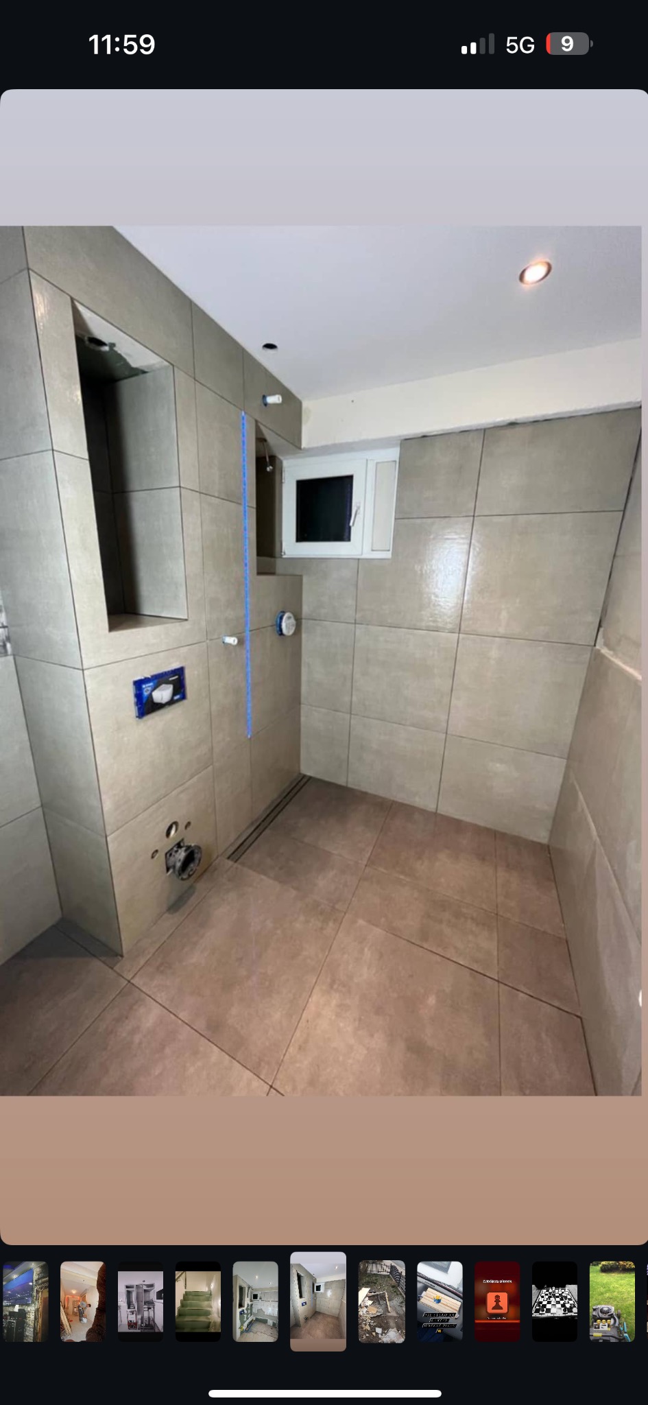 Łazienka w trakcie prac wykończeniowych: ułożone płytki podłogowe i ścienne w odcieniach beżu, widoczne podejścia wodno-kanalizacyjne i częściowo zamontowany stelaż podtynkowy WC, pionowa poziomica...