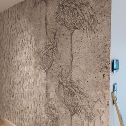 Grzegorz gzik - Teksturowana ściana z dekoracyjnym rysunkiem flamingów, obok pionowa poziomica i nowoczesny panel sterowania na białej ścianie.